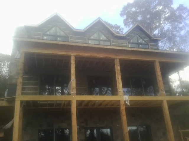 Dormers and porch framing on a large log home under construction — Roof Coating work by our crew in Silvis