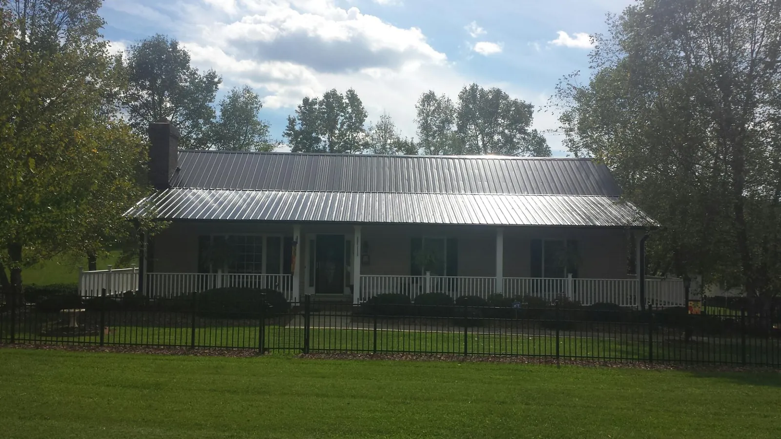 Gray metal roof on a brick ranch with a full width front porch — Gutter Guard Installation work by our crew in Silvis