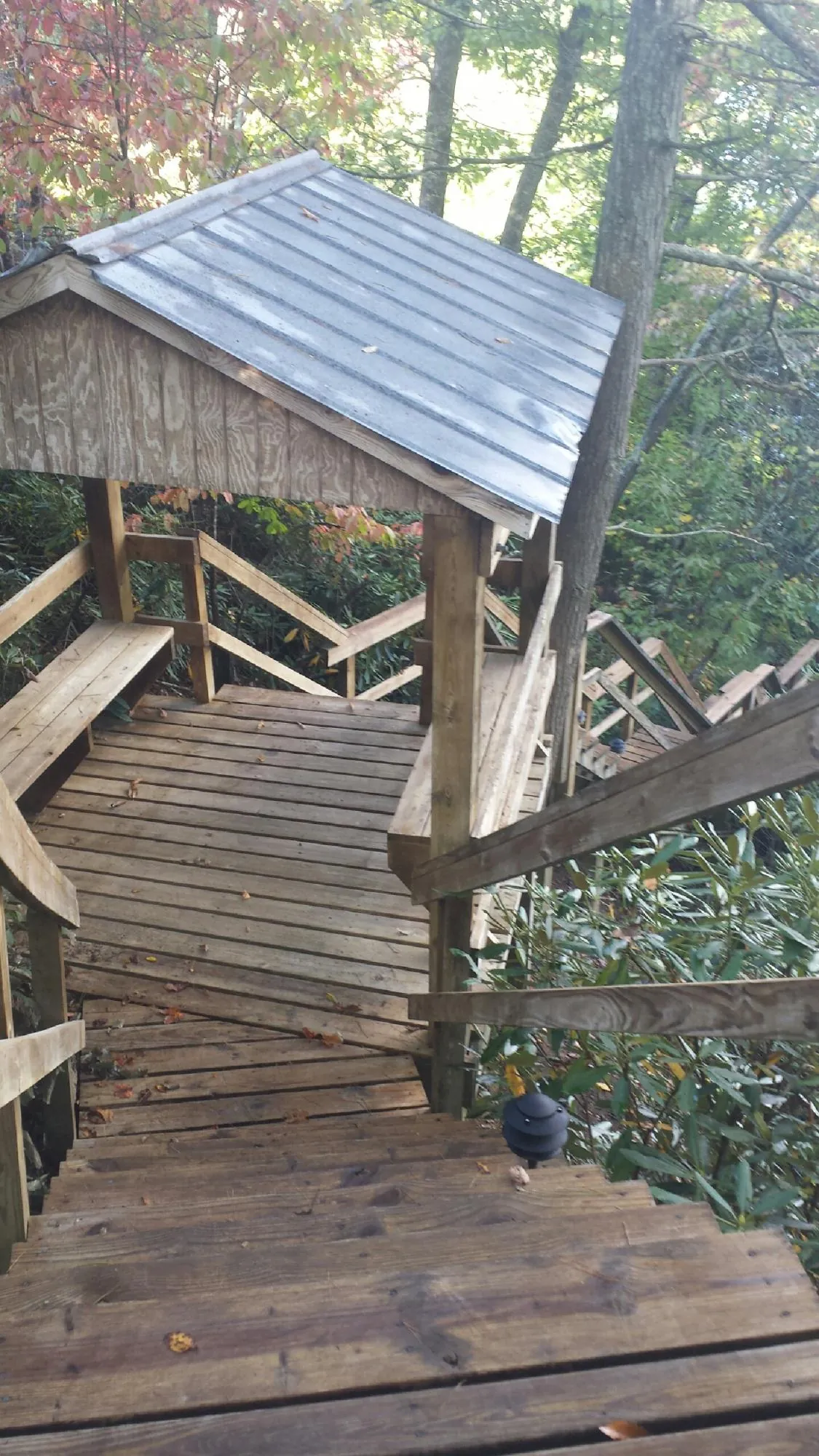 Metal roofed shelter over wooden steps on a wooded walkway — Skylight Repair & Installation work by our crew in Silvis