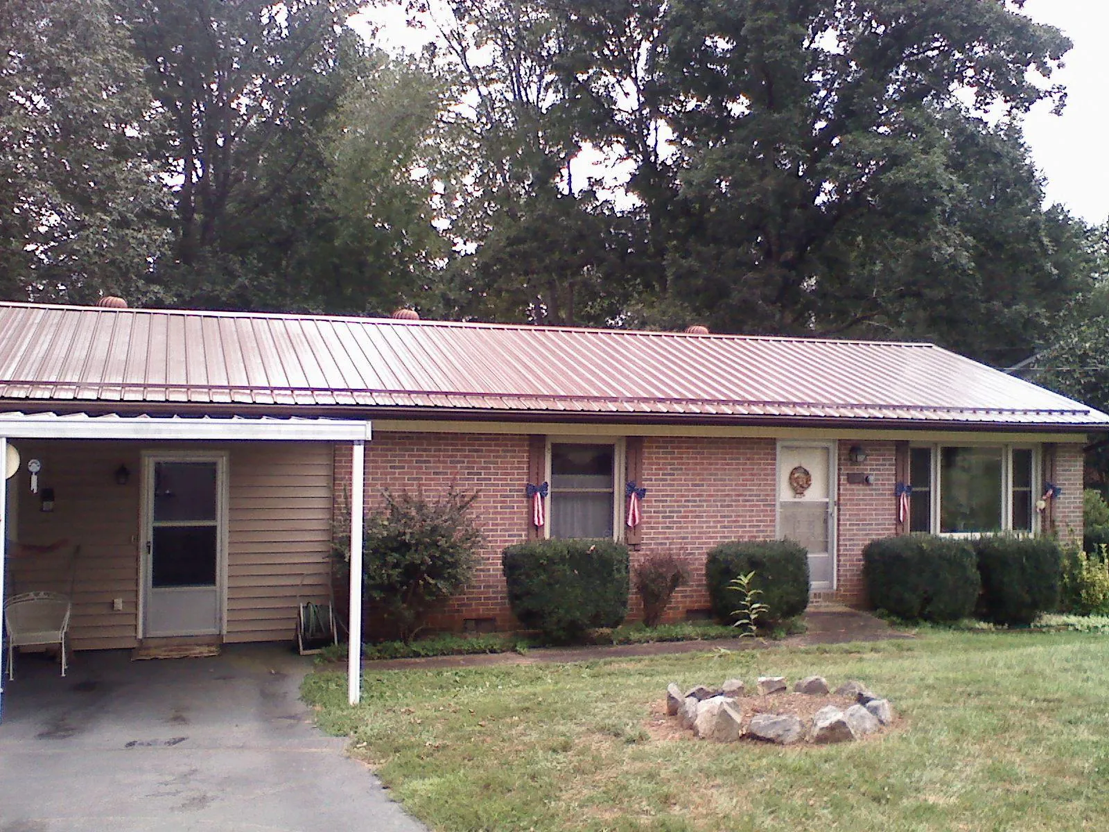 Bronze metal roof and carport on a brick ranch home — Roof Repair work by our crew in Silvis